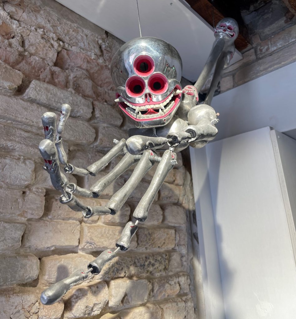 silver skull and skeletal hand Citipati suspended from ceiling